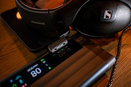 Mustad Sennheiseri kõrvaklapid laual sisselülitatud ekraaniga kaasaskantava audiopleieri kõrval