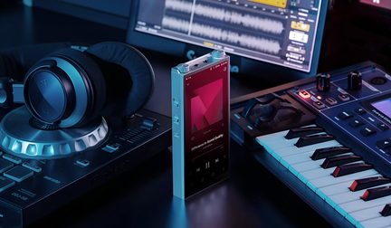 Gümüş renkli taşınabilir audiophile müzik çalar, ekranı açık, stüdyoda DJ kulaklığı ile master klavye arasında dikey olarak konumlandırılmış