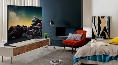 Samsung QE65Q900R-tv i en moderne stue, der viser et billede af klipper i rummet, rød lampe og stol