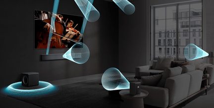 Černý matný kovový obdélníkový soundbar zepředu pod nástěnným televizorem s černým plastovým krychlovým subwooferem a dvěma kompaktními přídavnými reproduktory ve stejném designu umístěnými v moderním obývacím pokoji