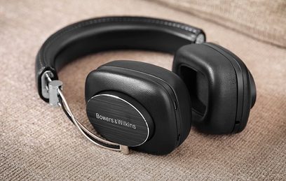 Bezdrátová sluchátka Bowers & Wilkins P7 Wireless v černé barvě, pohled z levého profilu, položená na béžové látkové ploše