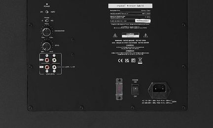 Černý kovový zadní panel basového reproduktoru, ovládací knoflíky pro crossover a úroveň, RCA vstupy, vypínač, IEC zásuvka