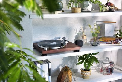 Giradischi in legno Audio Technica AT-LPW50BTRW su mensola bianca con piante, libri, diffusore e oggetti decorativi