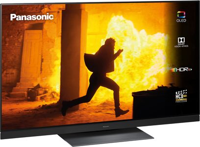 Panasonic TX-65GZ1500E OLED HDR10+ TV-skærm, der viser silhuetten af en sort person, der hopper foran en eksplosion af klart gult flammende ild
