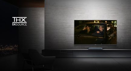 THX 4K Source TV on in a dark room, displaying a movie scene with two people in a car at night