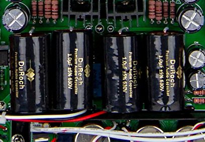 Nærbillede af Mundorf elektrolytiske kondensatorer på det grønne printplade i en sort PrimaLuna EVO 200 stereo-forforstærker