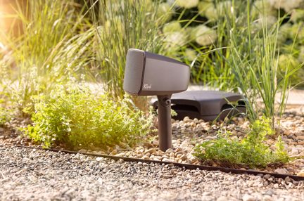 Outdoor garden speaker on a stake, dark grey with a matte plastic finish, front grille and swivel, side view