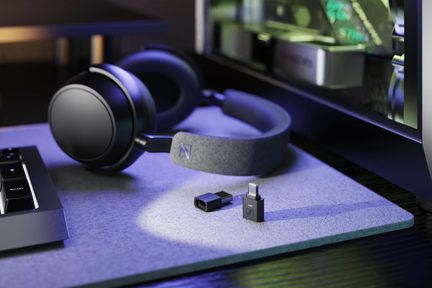Сірі бездротові ігрові навушники Sennheiser з чорними амбушурами та USB-A і USB-C донглами, розташованими на килимку перед ПК