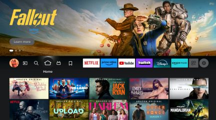 Brugergrænseflade med serieplakater, ikoner for streamingtjenester, karakterer i kostumer, blå himmel, ørken
