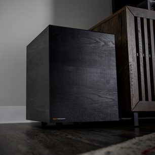 Soundbar Klipsch Cinema 600 din lemn închis la culoare, vedere din față în unghi, așezată pe un raft de lemn