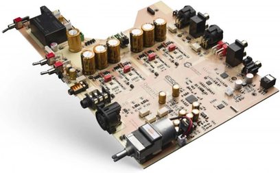 Hovedtelefon-forforstærker i høj kvalitet CMA EIGHTEEN MASTER, printkort set i perspektiv, cylindriske guldfarvede kondensatorer, sorte og røde lydstik, sorte rektangulære komponenter, lyse beige printplader, sorte tekniske inskriptioner, metalliske RCA-stik, sølvfarvet cylindrisk motor med kabler, roterende potentiometer, symmetrisk opstilling af elementerne