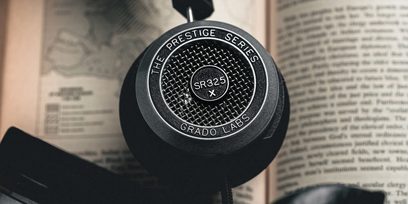 Offener Hi-Fi-Kopfhörer Grado SR325x, Nahaufnahme der rechten Lautsprecherkalotte vor unscharfem Texthintergrund einer Broschüre