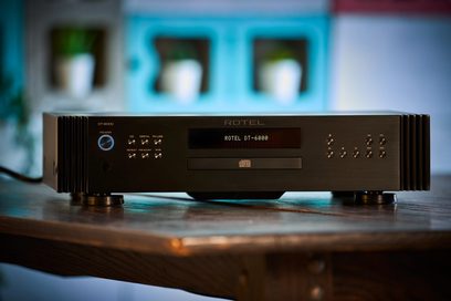 Rotel DT-6000 sort CD-afspiller, set forfra, placeret på en træoverflade, med en oplyst blå skærm i baggrunden