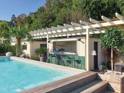 Rechthoekig zwembad met bar, witte pergola, palmbomen, groene planten, in een bestrate binnenplaats voor een modern huis