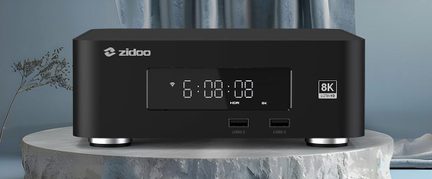 Matně černý kovový multimediální přehrávač, pohled zepředu, centrální digitální displej 6:08:08, dva porty USB 2.0, odznak 8K Ultra HD