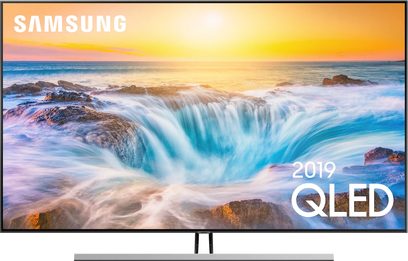 Samsung QE55Q85R-tv, der viser en tyrkisfarvet brydende bølge på en strand ved en orange solnedgang