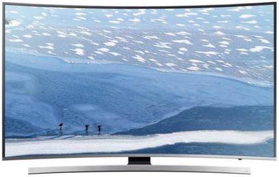 Zakrzywiony telewizor Samsung UE55KU6640 wyświetlający obraz trzech narciarzy na zaśnieżonym stoku z chmurami w tle
