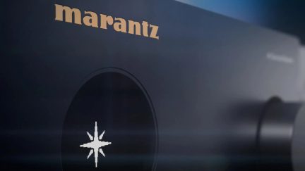 Sort Marantz-lydforstærker, nærbillede af det gyldne logo og en drejeknap på fronten