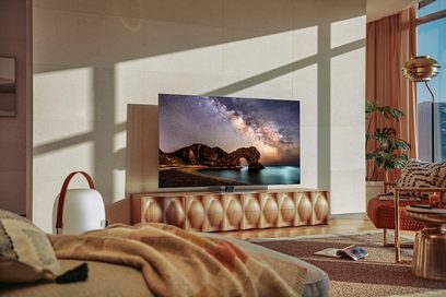 Samsung QE85QN85A TV som viser et steinlandskap og en stjernehimmel, plassert på et trehylle i en stue