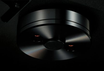 Underside view of a black circular base with a central button and two recessed screws