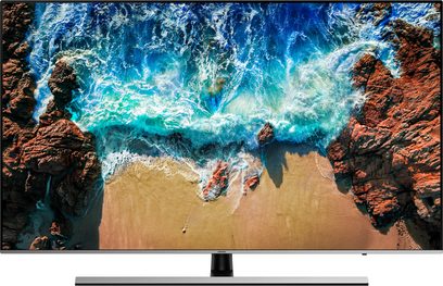 Samsung UE82NU8005-fjernsyn viser et luftfoto af en bugt omgivet af klipper, turkisblåt vand og gyldne sandstrande