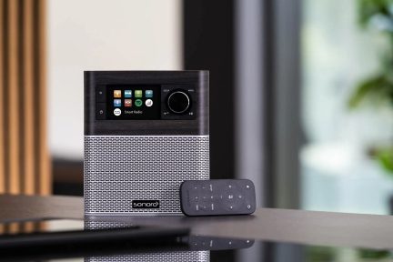 Έξυπνο ραδιόφωνο Sonoro Stream με οθόνη αφής που εμφανίζει εικονίδια εφαρμογών, τοποθετημένο σε ξύλινο σκούρο τραπέζι