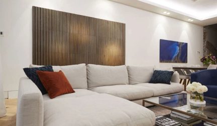 Beige hjørnesofa med puder i et moderne stue med en træskillevæg, et sofabord og et blåt maleri på væggen