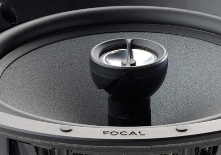 Primo piano leggermente dall'alto di un altoparlante coassiale circolare in metallo e plastica nera e grigia, cono grigio antracite con texture circondato da una sospensione in gomma nera, tweeter centrale cilindrico nero sormontato da un piccolo cupolino metallico, logo FOCAL inciso sulla flangia anteriore.