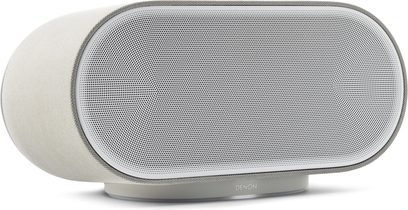 Lysgrå Denon Home 600 smart-højttaler i vandret, oval form med stor metalfrontgrill, set i trekvart profil