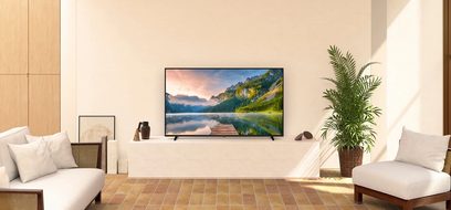 Televisore Panasonic TX-65JX800E che mostra un paesaggio montuoso e lacustre in un soggiorno moderno e luminoso