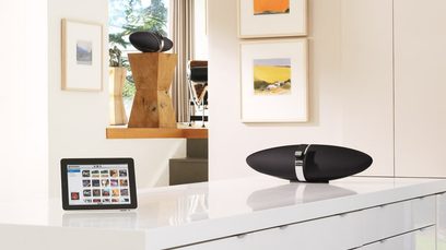 Must Bowers & Wilkins Zeppelin Air õhukõlar tseppeliini kujuga, valge laua peal riiulite ja raamidega