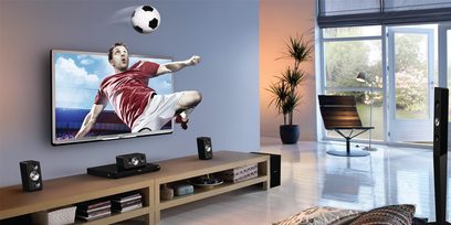 Philips 40PFL5507 fladskærms-TV, der viser en fodboldspiller i aktion, højttalere, DVD-afspiller på et lyst trækabinet