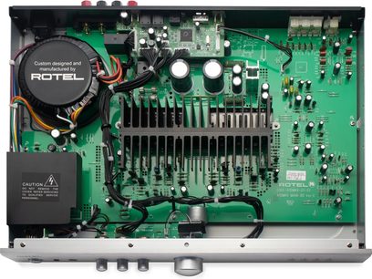 Integrovaný stereo hi-fi zesilovač Rotel A10 MKII, pohled shora, zelený tištěný spoj, elektronické součástky, černý chladič, kruhový transformátor, vícebarevné kabely, stříbrný kovový kryt