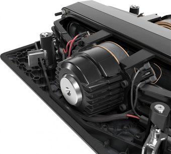 Indbygget subwoofer SFC-12-SW, nærbillede, sort cylindrisk centralmotor med køleribber, røde og sorte kabler tilsluttet, sort metalstruktur, synlige mekaniske og elektroniske komponenter, sort perforeret bund