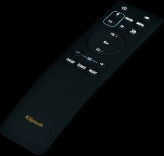 Zwarte Klipsch Cinema 800-afstandsbediening met grijze en gouden knoppen, bovenaanzicht op zwarte achtergrond