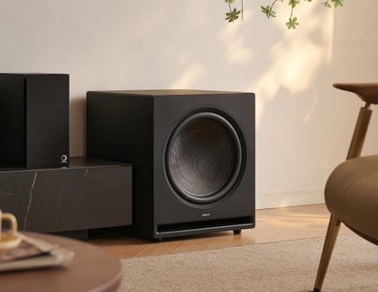 Černý matný subwoofer, skříňka z dřeva/kompozitu, široký přední reproduktor a spodní basový port, pohled ze tří čtvrtin