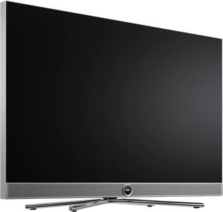 Telewizor Loewe Vega 43 czarny z płaskim ekranem, cienka srebrna ramka, widok z przodu pod lekkim kątem z krzyżową podstawą