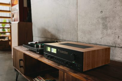 NAD C3050 Standard Edition svart hi-fi stereoanlegg, forfra, plassert på et trehylle i et rom med betongvegg