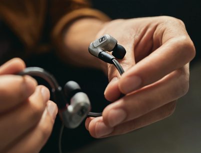 Sennheiser IE 600 in-ear hodetelefoner holdt i hender, metalltupper, svart kabel