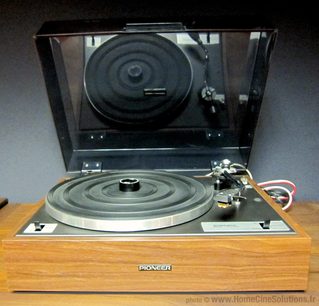 Pioneer PL-10 pladespiller placeret på en træsokkel, set forfra i et skråt perspektiv, låget er lukket, tonearmen er synlig
