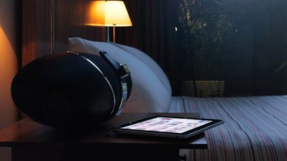 Must Bowers & Wilkinsi Zeppelin Air kõlar, selle ees sülearvuti puutetahvliga, taustal põlev lamp