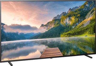Televisore Panasonic TX-65JX800E che mostra un paesaggio di montagne boscose e un lago che riflette un cielo nuvoloso al tramonto