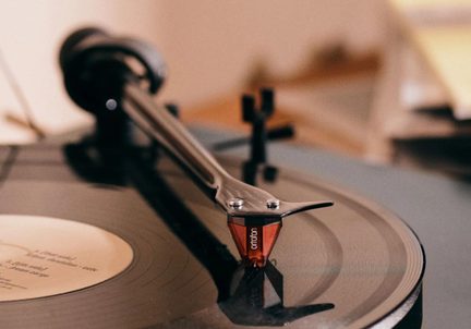 Vinylspelare med röd Ortofon-pickup och tonarm på svart skiva i närbild