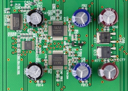 Zelený DPS s měděnými ploškami, pohled shora, integrované obvody AKM a hliníkové elektrolytické kondenzátory