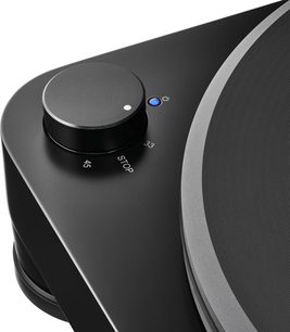 Garso grotuvų „Audio Technica AT-LP7X“ patefono stambus vaizdas: juodas diskas ir 33/45 greičio pasirinkimo jungiklis su mėlyna indikacine lempute