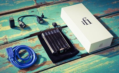 Bærbar iFi xDSD sort audio-konverter, blå USB-kabel, på slidt turkis træbaggrund