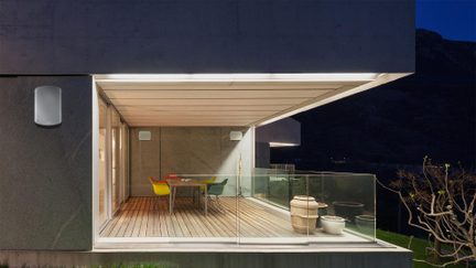 Applique da parete esterna LED bianca dal design arrotondato su facciata di terrazza moderna illuminata