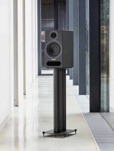 Ηχείο βιβλιοθήκης PMC Prodigy1 μαύρο σε βάση, όψη από μπροστά, σε εσωτερικό χώρο με παράθυρο από το δάπεδο μέχρι την οροφή