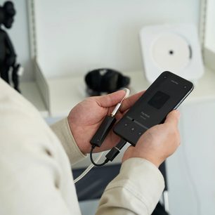 Håndholdt sort Astell&Kern AK HC3 bærbar audio-konverter set forfra, tilsluttet et hvidt kabel