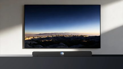 Soundbar nera sotto televisore a parete a grande schermo, vista frontale in un soggiorno moderno